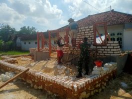Babinsa Yudi Bantu Warga Pasang Kusen Pintu dan Jendela di Desa Braji