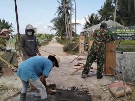 Bakti TNI di Kecamatan Lenteng Serka Huda Bersama Warga Laksanakan Pengecoran Tiang Sandaran Jembatan